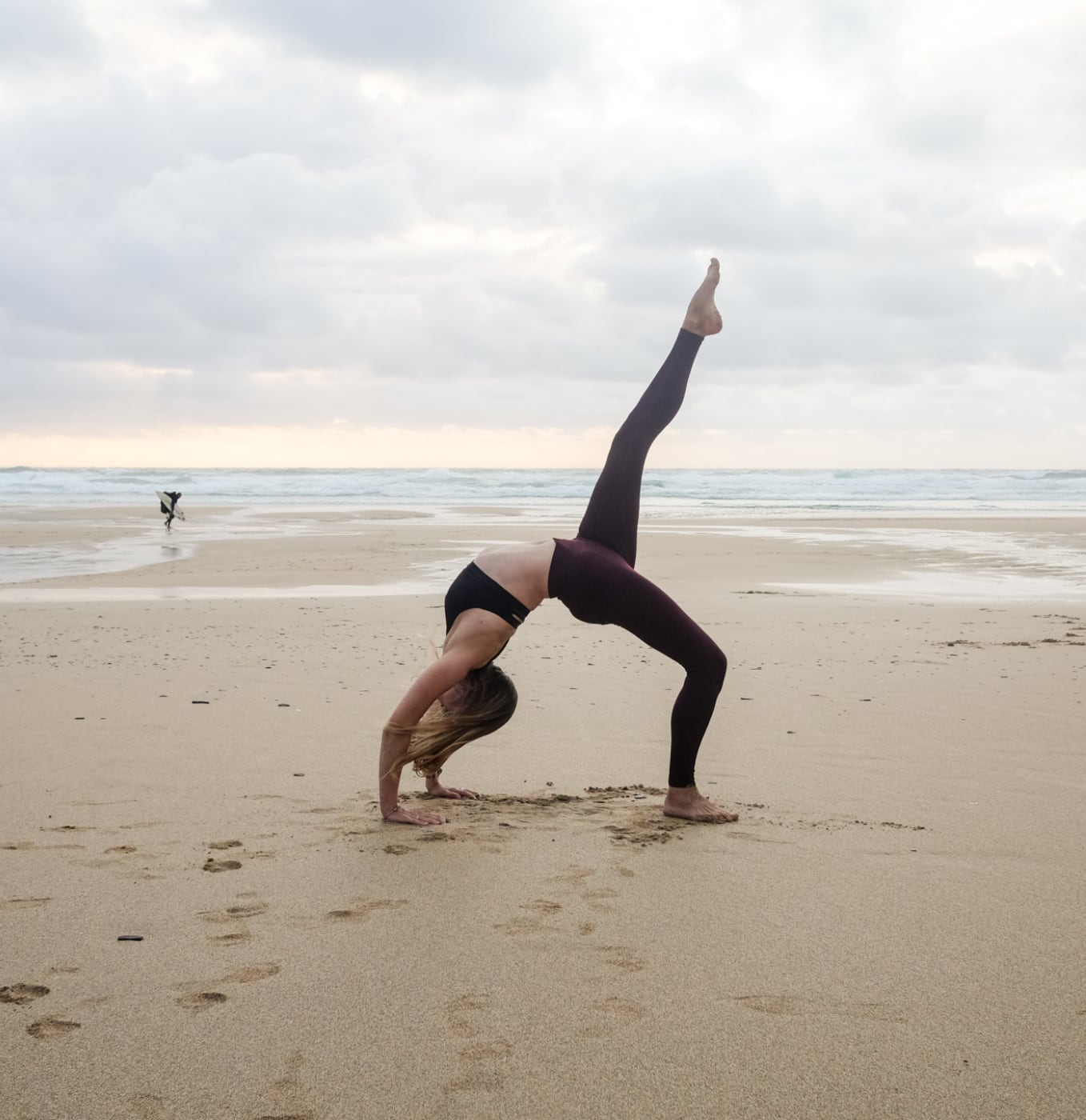 yoga wheel pose on the beach